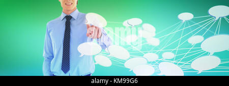 Mid section of smiling businessman using interface while standing with hand in pocket against abstract green background Stock Photo