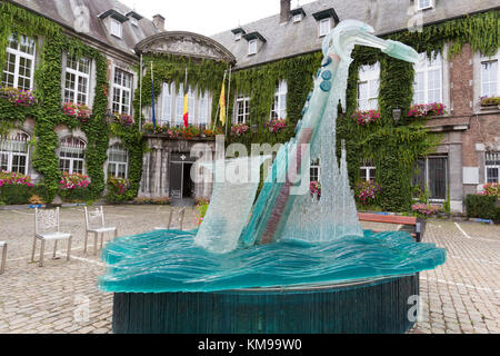 Town of Dinant, Belgium. Picturesque view of the Bernard Tirtiaux glass saxophone fountain sculpture, with Dinant Town Hall in the background. Stock Photo