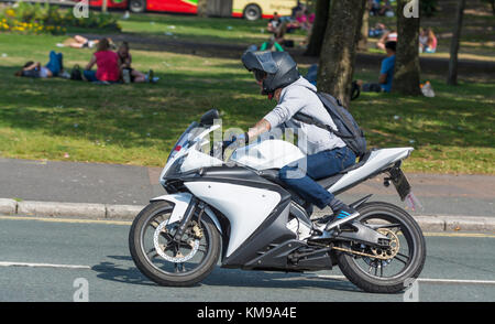 Man riding a motorbike without wearing any protective clothing other than a crash helmet, in the UK. Stock Photo