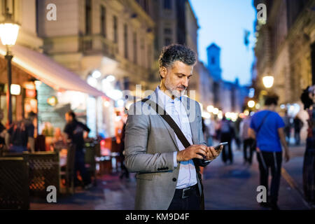 Mature businessman with a smartphone in a city. Stock Photo
