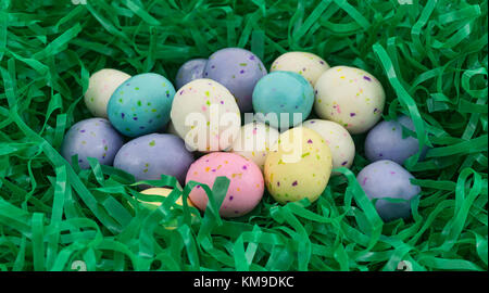 A group of speckled Easter egg malt ball candies nestled in a green plastic grass. Stock Photo