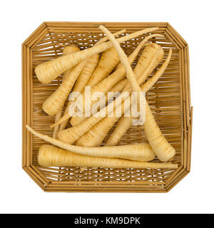Top view of a small wood basket filled with whole parsnips isolated on a white background. Stock Photo