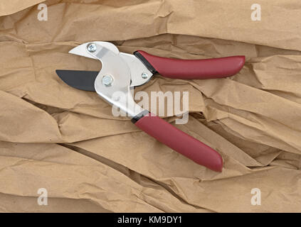 A pair of open pruning shears on brown wrinkled paper. Stock Photo