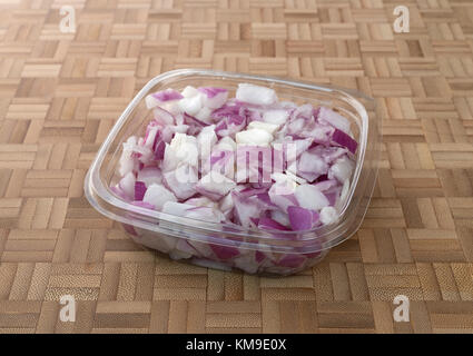 A small plastic container of freshly chopped red onions on a wood bamboo cutting board. Stock Photo