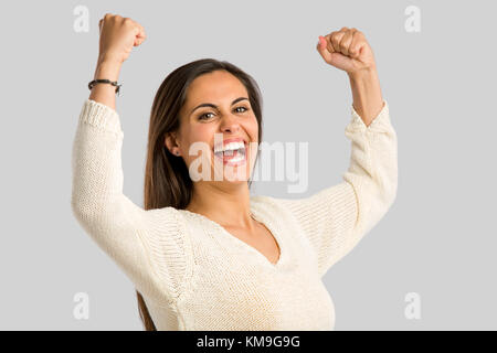 Studio shot of a happy young woman with arms raised Stock Photo