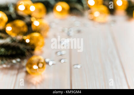 Christmas blurred background with a glowing garland golden bokeh on white wooden table. A beautiful holiday idea for postcards and posters. Free space Stock Photo