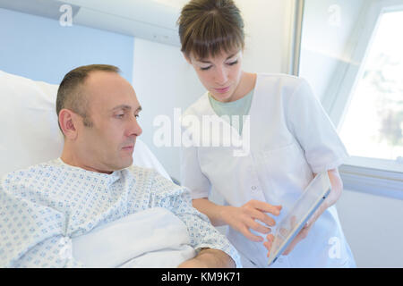 female nurse takes care of man in bed Stock Photo