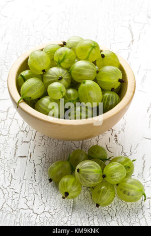 Heap of ripe, fresh harvested green gooseberry fruit in wooden bowl on white table background Stock Photo
