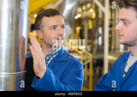 two workers at plant checking parameters of pressure Stock Photo