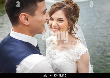 Attractive bride and groom smiling near the lake