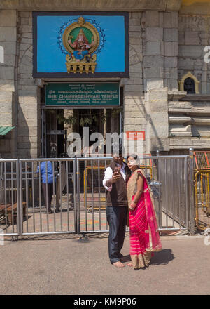 Young Indian couple standing and taking selfie in front of the Shri Chamundeshwari Temple at Mysore, Mysuru, Karnataka, India. Stock Photo