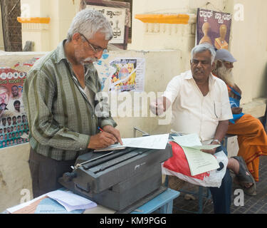 Customer paying street typist  on footpath at Mysore, Mysuru, Karnataka, India. Stock Photo