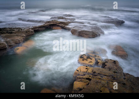 Waves breaking over coastal rocks Stock Photo