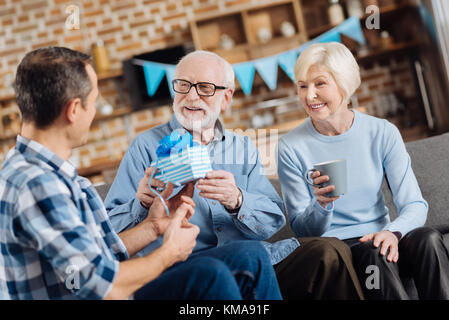 Loving son giving birthday present to his elderly father Stock Photo