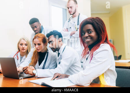 Multiracial team of young doctors working on laptop computer in medical office. Stock Photo