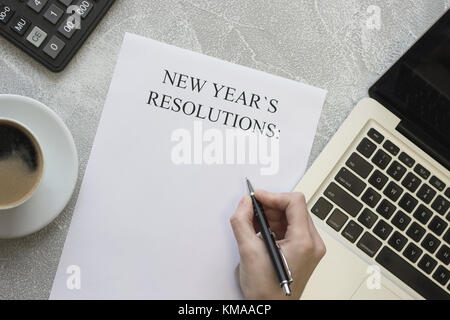 A hand writing New Year's resolutions, coffee, office supplies Stock Photo