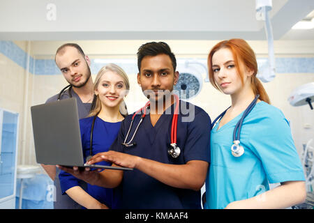 Multiracial team of young doctors working on laptop computer in medical office. Stock Photo