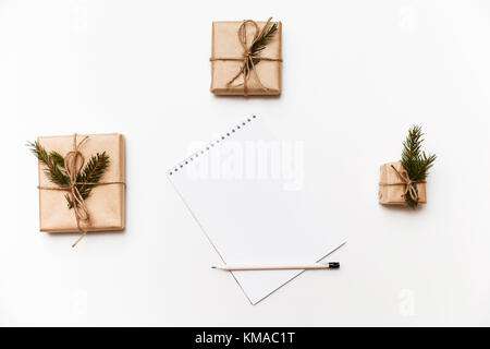 Empty notebook, pencil and gift boxes or presents packed in kraft paper isolated on white, top view Stock Photo