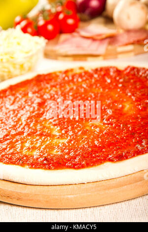 Raw pizza with ingredients in the bacground Stock Photo