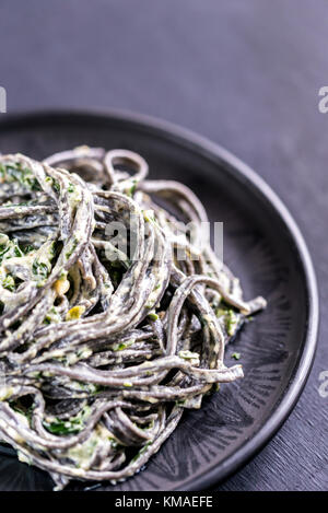 Black pasta with spinach, mascarpone and Parmesan Stock Photo