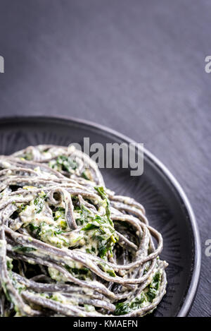 Black pasta with spinach, mascarpone and Parmesan Stock Photo