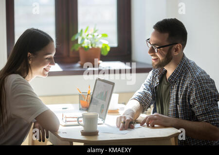 Businessman and businesswoman have meeting in office and discussing successful project. Two millennial employees talking about new model of business a Stock Photo