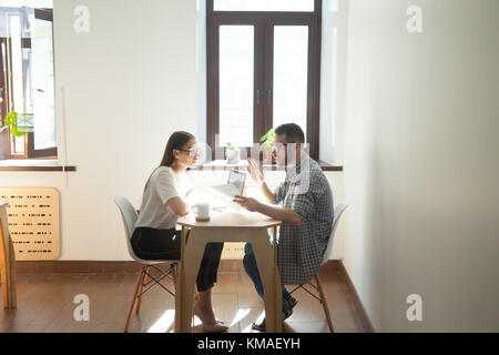 Businessman and businesswoman discussing working problems in office. Two millennial employees having business meeting and arguing job questions Stock Photo