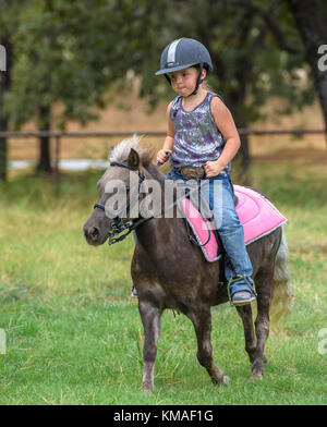 Four year old girl riding pony. Stock Photo