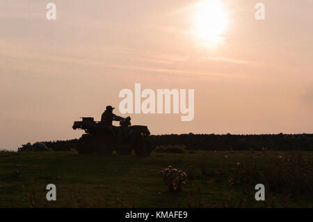 Young man riding a quad (ATV) on farmland in Weardale in County Durham, North East England as the evening light starts to fade. Stock Photo
