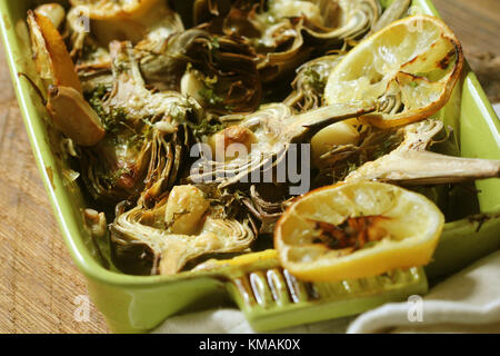 fried artichokes with garlic and lemon on pan on rustic table Stock Photo