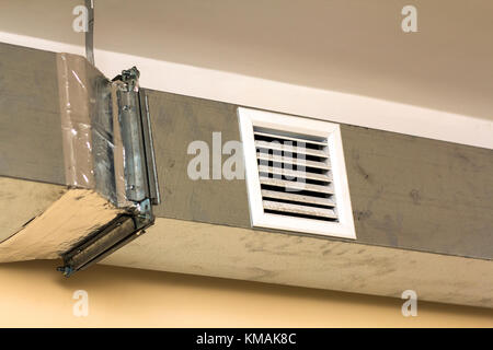 Ventilation pipes in silver insulation material hanging from the ceiling inside new building. Stock Photo