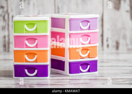 Small, cute and colorful plastic drawers on white wooden background Stock Photo