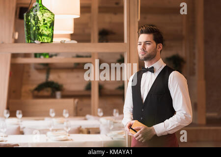 Waiter standing with notebook and pen Stock Photo