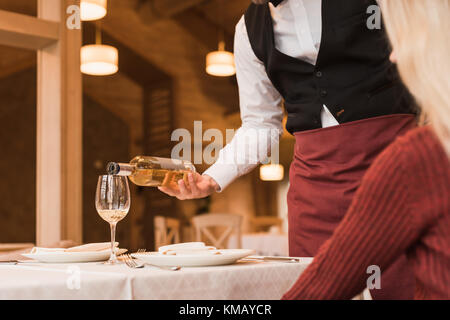 Waiter pouring wine into glass Stock Photo