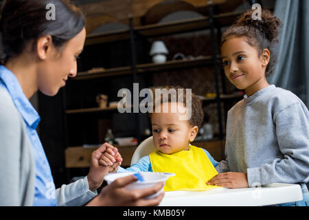 mother and daughter feeding baby Stock Photo