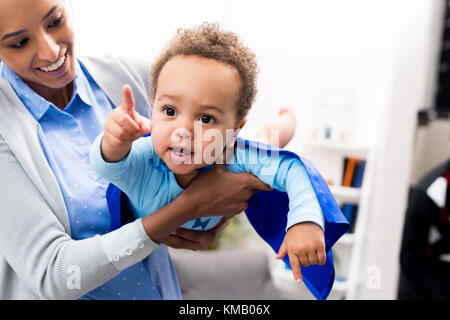 mother holding son in superhero costume Stock Photo