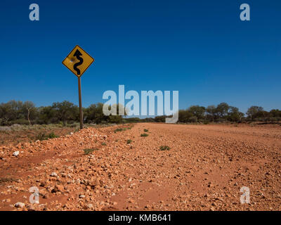 A 'Curves Ahead' road sign with bullet holes on the Gunbarrel Highway, Western Australia Stock Photo