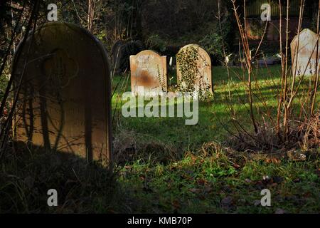 Old English cemetery with old gravestones and lots of undergrowth classic spooky style Stock Photo