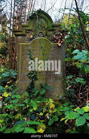 Old English cemetery with old gravestones and lots of undergrowth classic spooky style Stock Photo