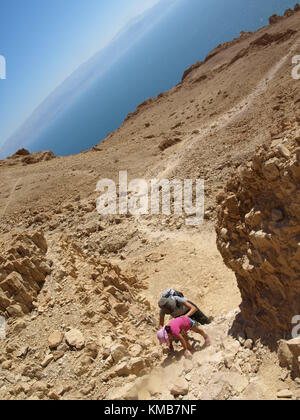 mother and child going uphill a mountain with the sea on the background Stock Photo