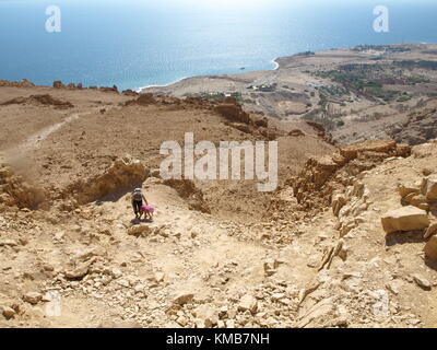 mother and child going uphill a mountain with the sea on the background Stock Photo