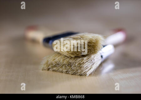 Pedzel for painting with oil paint on a wooden workshop table. A bristle brush in a workshop. Black background Stock Photo