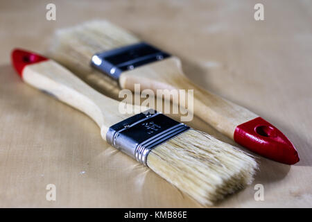 Pedzel for painting with oil paint on a wooden workshop table. A bristle brush in a workshop. Black background Stock Photo