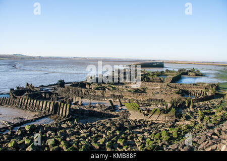 Remains of discarded river barges rotting in the mud on the Swale estuary Stock Photo