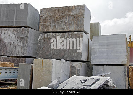 Stacks of heavy granite stones extracted from natural stone quarry. These blocks are processed by cutting and polishing to make wall and floor slabs. Stock Photo