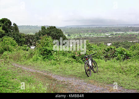 Cycle parked during off road cycling along rough countryside roads covered with lush foliage and scenic aerial views near Bambolim in Goa, India Stock Photo
