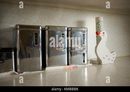 Set of kitchen storage boxes for bulk products - several boxes of different sizes made of stainless steel and towel holder in the shape cute white duc Stock Photo