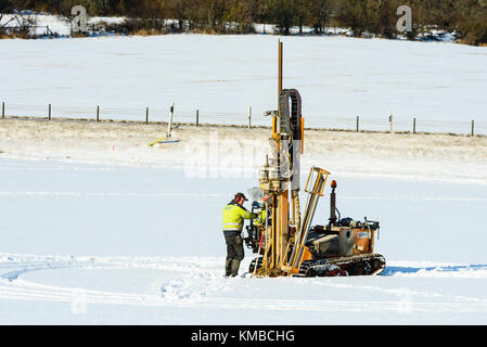 Lyckeby, Sweden - February 13, 2017: Real life documentary of exploratory drilling in the ground on a snow covered field with road in background. Stock Photo