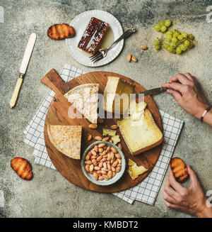 Cheese platter with female hands reaching to food, flat-lay Stock Photo