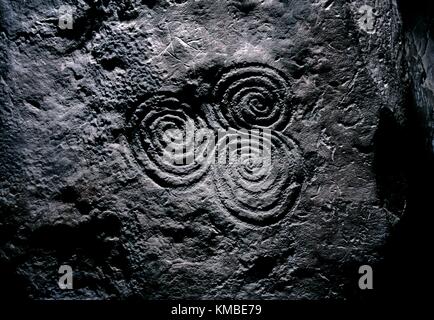 The famous carved stone triple spiral triskele motif in the central chamber of Newgrange prehistoric mound in the Boyne Valley. Stock Photo